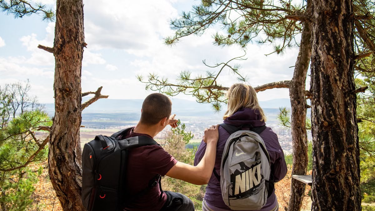 A couple enjoying a break on a forest bench with a scenic view, perfect for nature and lifestyle themes.